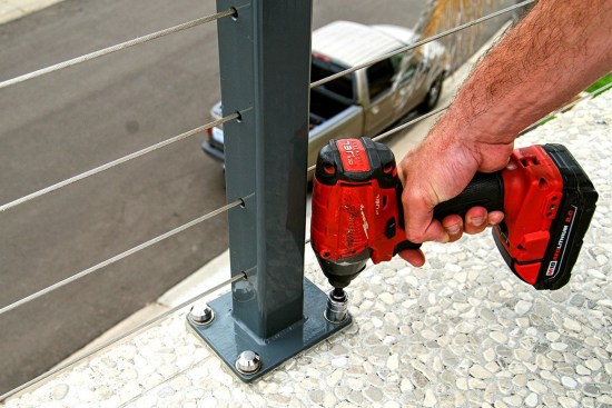 The posts have hefty 4-inch-by-5-inch base plates, which were fastened to the deck framing with 4-inch-long, 3⁄8-inch-diameter lag screws.