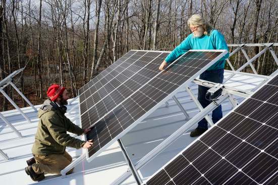 David Kelly and Sonny Searles of House Revivers set solar panels on a Bangor, Maine, roof in 2017 (photo by Ted Cushman).