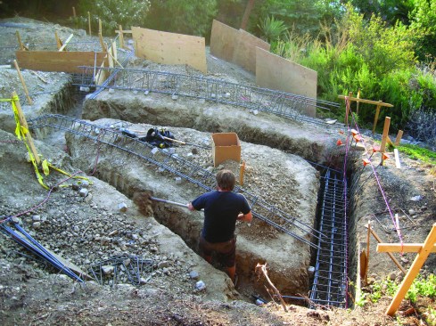 A worker shovels out the trench for grade beams that will support the stem wall for the unconditioned crawlspace under Sylvia Wallis’ addition.