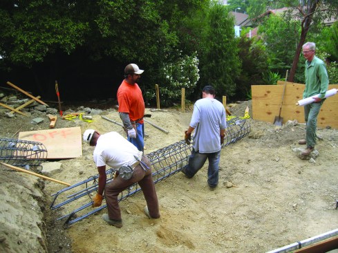 Foundation workers set rebar cages for deep structural piers into the hillside for Sylvia Wallis’ high-performance addition.