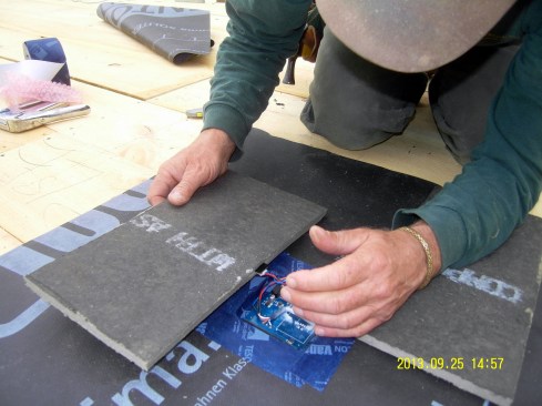 Chris Miksic inserts a moisture sensor in the Homasote fiberboard underlayment for a mambrane roof installed over an unvented flat roof framed with wood I-joists and insulated with dense-blown cellulose in rural Vermont.