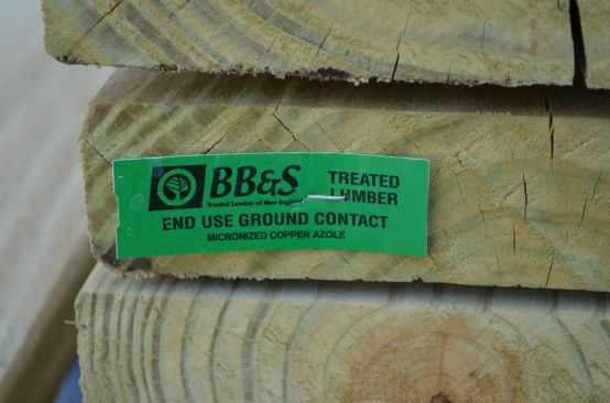The beam is framed with preservative-treated lumber that is rated for ground contact, as required by industry standards.