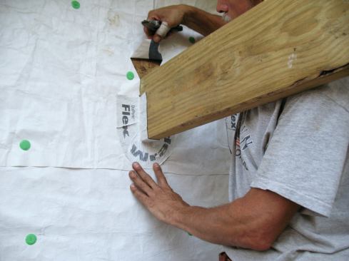 Before installing the upper piece of flashing, I make a pair of 3-inch-long diagonal cuts in the housewrap, starting at the top corners of the joist, to create a head flap.