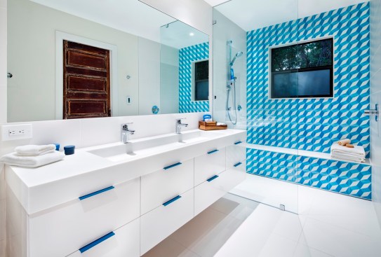 Bright blue tiles and coordinating drawer pulls provide a pop of color in this bathroom remodel by Mark Evans