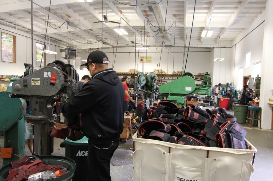This machine operator is riveting leather hammer loops onto nylon and leather tool bags.