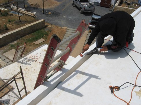 The roofer presses down on the TPO seam with a roller to achieve a good bond for a durable, watertight seal.