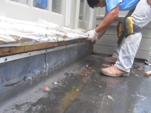 This EPDM roof turns about 10 inches up the wall (8 inches is BOWA's normal requirement), and a termination bar holds it firmly in place. Sealant at the top edge prevents water from leaking behind it. Finally, the weather-resistive barrier (WRB) on the wall is pulled out in front of the roofing material. 