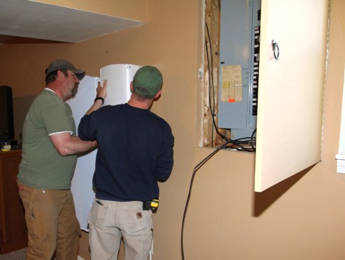 Ritz and Millette set the SolarEdge inverter onto its mounting bracket. The inverter converts direct current (DC) from the Tesla battery into alternating current (AC) for use by the home or for transmission into the Green Mountain Power distribution network.