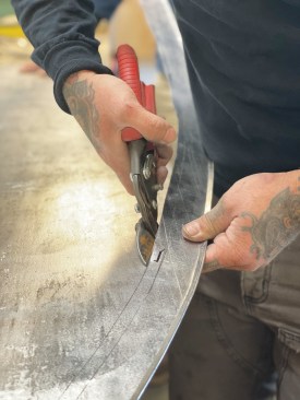 Ouelette cuts the hemmed and rolled drip edge off the sheet.