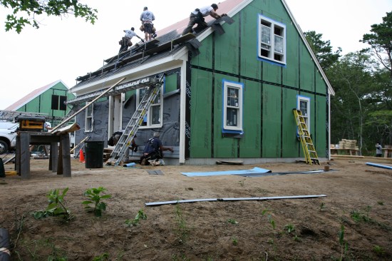 9:37a: Roofers blast their way up the west roof while a crew below starts running clapboards. Roofing would be completed by noon.