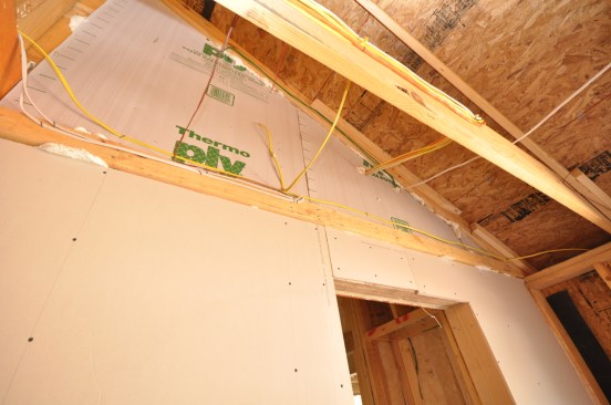 Large openings, such as the opening into an attic from an attached garage, get sheathed and the edges foamed.