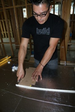 To seal rim joists, a carpenter cuts blocks from rigid foam using a template that has notches for the top and bottom flanges of I-joists.