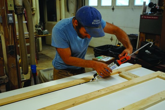 Then he applies a generous bead of black silicone caulk where the edge forms meet the worktable.