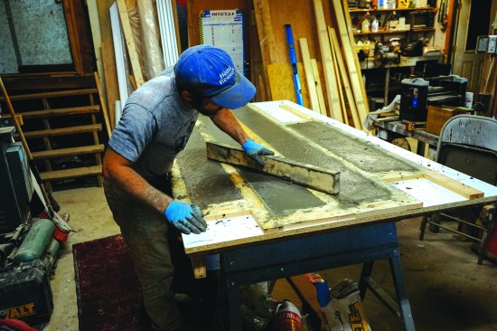 He strikes the material off with a 2x4 screed.