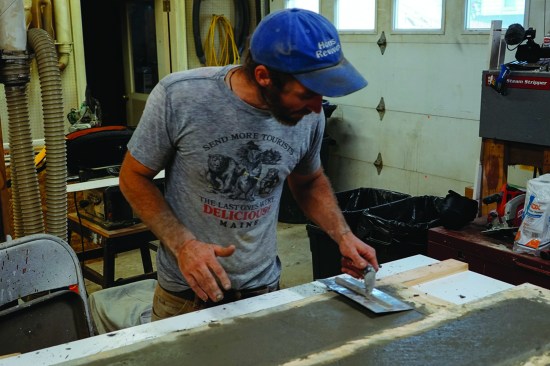 After allowing the concrete to set under a tarp for a few hours, he trowels the surface, then covers the sills again to let them cure.