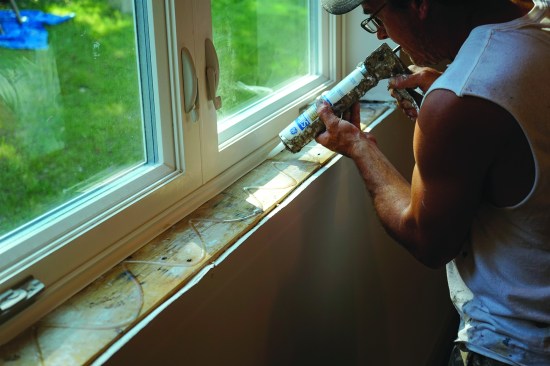 On site, the installers apply a setting bed of silicone caulk to the rough framing.