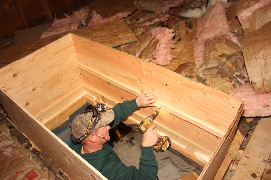 Clement screws a ledger to the plywood hatch box.