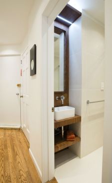 An elongated custom bamboo vanity and strategic lighting add drama to the entry of this former powder room that now serves as a full bath for a growing family residing in the Gramercy Park neighborhood of Manhattan.