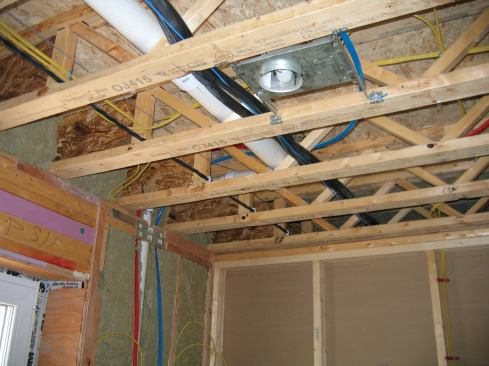 The line set (insulated with black foam insulation) and 4-conductor wire is laid through the open joist floor system.