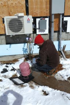 The tech tops off the lines with R410A refrigerant.