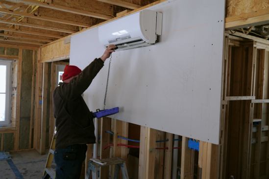 Inside, the tech tests the minisplit’s operation. He’ll run it in both heating and cooling modes before he leaves.