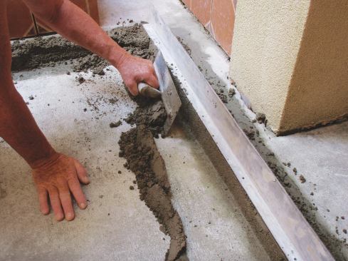 Trim away the loose mortar from the screed to make a better bonding surface for the bed mortar.