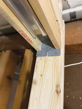 After making final adjustments so that the frame header would be perfectly level, the author fastened the brackets to the trimmers with screws supplied by the manufacturer.