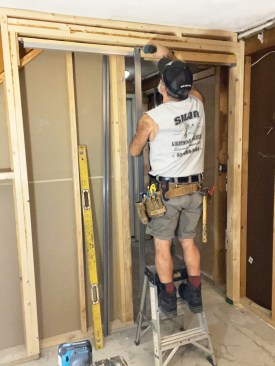 He positioned the first pair of split steel studs so that the tops of the studs butted against the header nailer, then fastened them with pan-head screws.