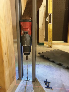 The author snapped chalk lines on the concrete floor to mark the rough opening. He used them to align the floor plate, which he fastened to the slab with Tapcon concrete screws.