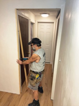 Once the finish flooring was installed, it was time to trim the door opening. To accurately locate the holes in the narrow edges of the split steel jambs for the trim screws and avoid deflections that could bend the flexible steel jamb, the author first partially drilled through the wood trim to mark the screw locations, then removed the trim piece to finish drilling the holes through the steel.
