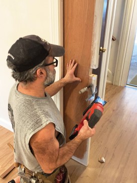 The author clamped a plywood backer to the back of the door before cutting out the latch opening with a jigsaw to prevent tear-out.