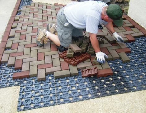 Azek’s lightweight pavers are made from old tires and recycled plastic and are installed over a plastic grid system, which locks the pavers in place.