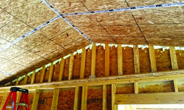 After attaching OSB to the underside of the scissors trusses and sealing the seams with tape, the author’s crew foamed the gaps in the gable end wall to contain blown insulation.