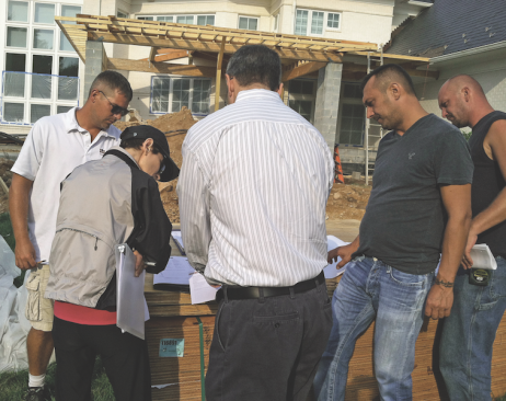 Frequent ad-hoc meetings between project managers, production managers, and trade contractors to iron out critical details help to keep jobs moving and on schedule. Here, metal roof details are being discussed with the roofing contractor.