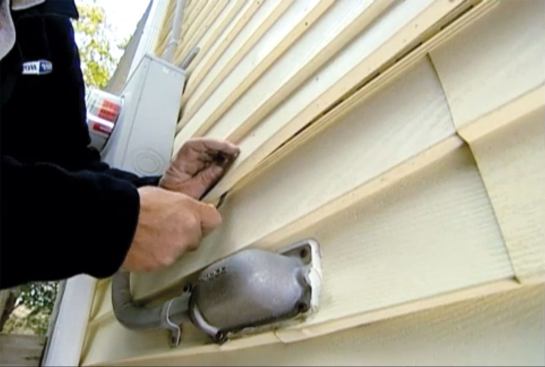 Finally, use the zip tool to reengage the patch to the panels above and below it. Hook the tool into the J-section at the butt, pull down, and slide the tool sideways while pressing against the siding with your palm to lock the pieces together again