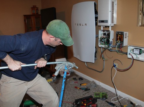 Electrician Scott Millette installs a Tesla Powerwall storage battery in a Vermont home in spring of 2016. (Photo by Tim Healey/JLC)