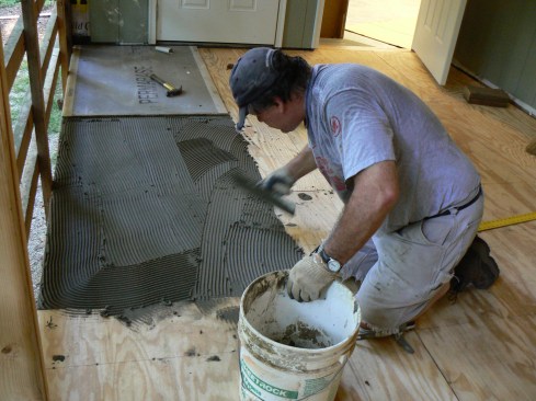 The author replaced the original porch subfloor with new 3/4-inch APA-rated tongue-and-groove Sturd-I-Floor sheathing, which is fastened to the framing with both 2-inch deck screws and construction adhesive. Next, he combed out unmodified thinset adhesive with a 1/4-inch square-notched trowel, set PermaBase exterior-rated cement backerboard on the furrowed mud, then fastened the backerboard to the subfloor with 1 1/2-inch roofing nails spaced about 8 inches o.c.