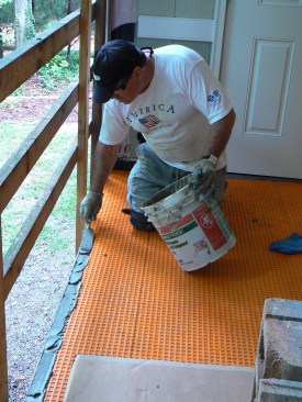 To finish the open edge of the porch, the author installed Shluter's  Rondec-Step metal trim, first spreading a bed of thinset over the membrane.