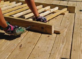 Figure 11. Spreading wood balusters out on pieces of 1-inch-thick decking centers them perfectly on 2x4 rails. An impact driver makes quick work of the 3 1/2-inch screws that join the parts.