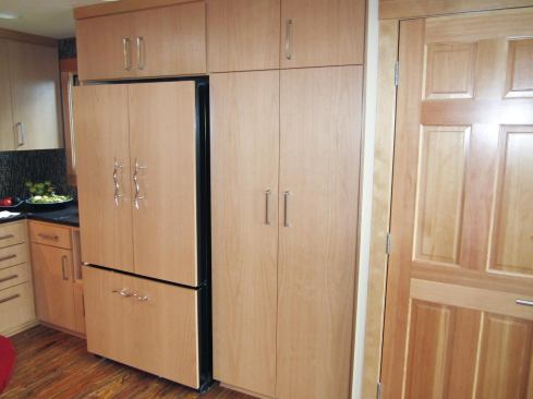 The cabinet above the refrigerator was built with a full-length side panel running down to the floor on the left of the fridge.