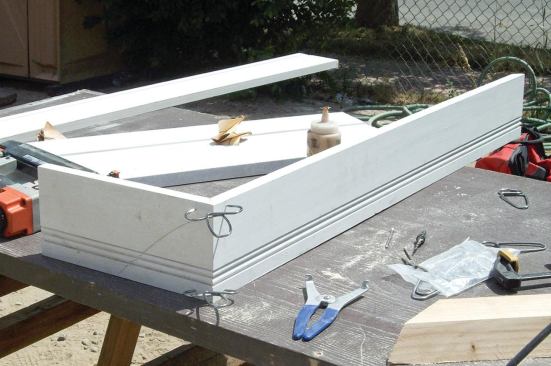 Next, we preassembled as many of the trim parts as possible on the ground, including the fascia — shownglued and clamped with Collins miter clamps. . . .