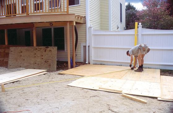 Swinging a tape from a wooden stake, the author lays out the inner and outer arcs of the stair at full scale on a double layer of plywood.