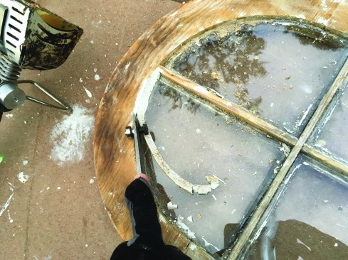 Once softened, the glazing putty can be easily peeled away from the window frame. Note: while not required on this job, aluminum foil can be used to shield
historic glass.