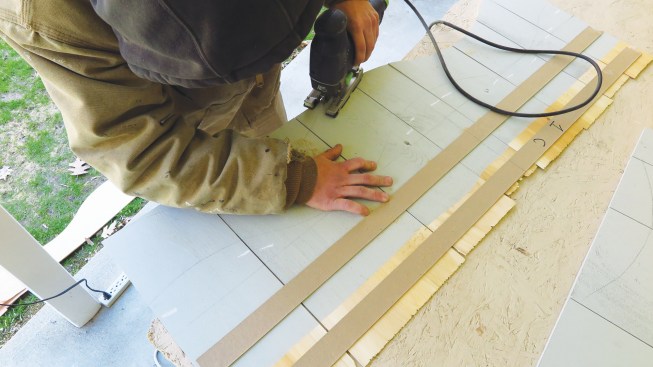 After the strips for four or five courses have been assembled, a worker cuts the waves on each section with a jigsaw.