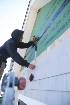 A worker snaps a plumb centerline on the gable wall to guide the installation of the shingle strips.