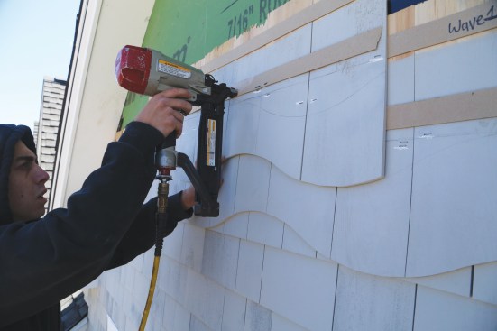 He then drives fasteners at the chalk marks made earlier, when the shingles were laid out on the bench.